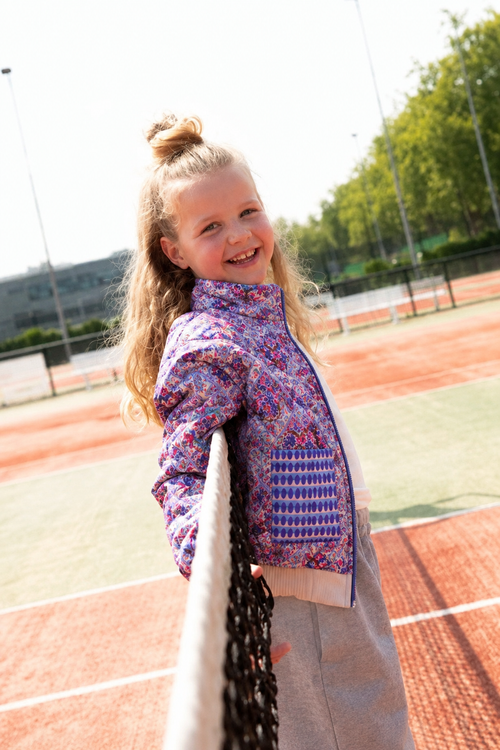 Blauw Alix gewatteerd meisjesjack op het model bij het tennisnet