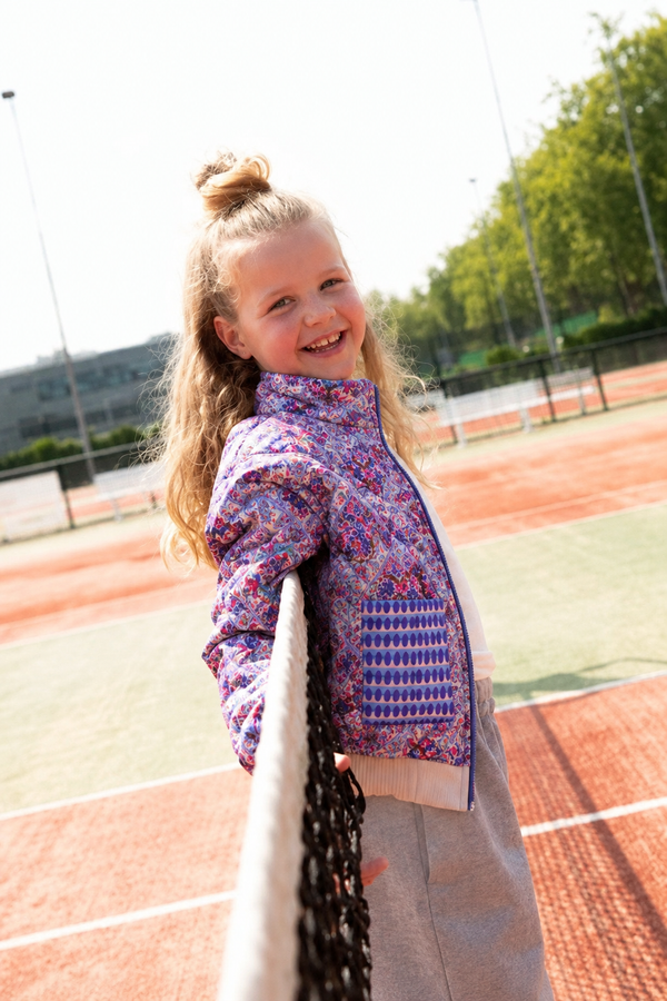 Blauw Alix gewatteerd meisjesjack op het model bij het tennisnet
